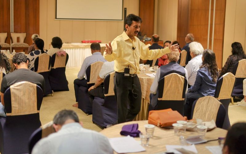 Dr. Singhvi leading an interactive health workshop with participants seated at round tables